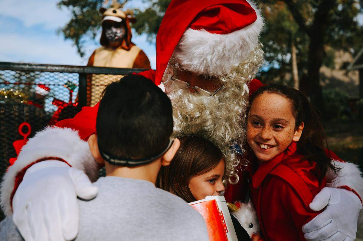 Santa (Phil Dellenger) hugs a group of neighborhood kids who came up to visit while at a home in Biloxi Saturday, Dec. 19, 2020. Each child was given a small gift and candy.