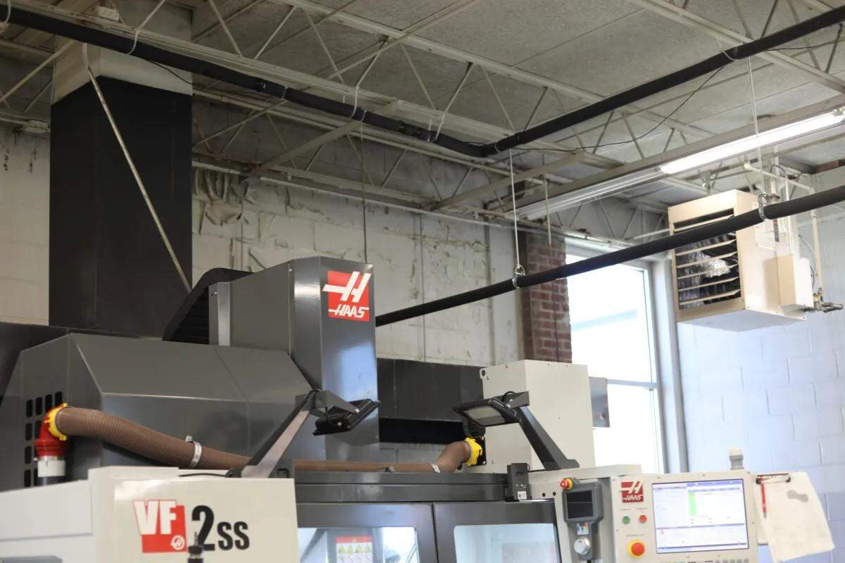 NEMCCs new precision manufacturing machines sit a few feet away from a wall with visible water damage.