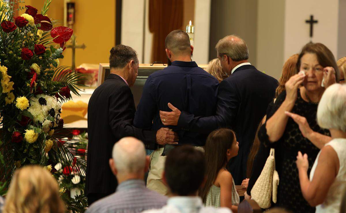 Doug Seal, right, son Cody Seal, center, and uncle Buddy Seal, left, view Cayce Seal’s body in a handmade casket at St. Clare Catholic Church on July 1, 2021, during the funeral services for Cayce, an Entergy lineman who died after working on power lines in New Orleans.