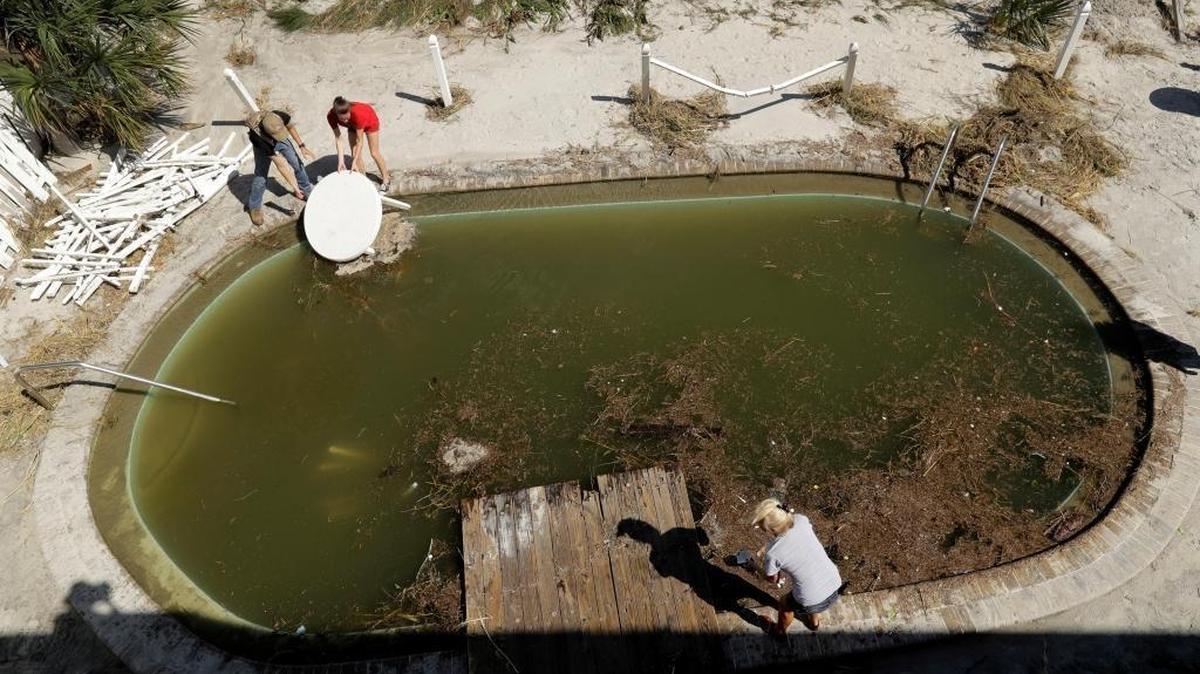 Volunteers clears debris from from a pool at a condo in Jacksonville Beach, Fla. Saturday, Oct. 8, 2016 after Hurricane Matthew passed through Friday. Scientists worry that the Zika virus that has touched down in South Florida is now a greater threat to expand and move up the coast.