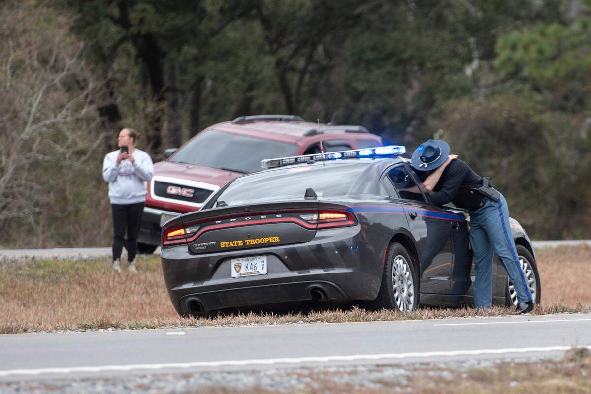 A state trooper hugs someone as a procession escorting George County Sheriff’s officer Jeremy Malone, who was killed on Thursday, arrives at Moments Funeral Home in Lucedale on Friday, Jan. 5, 2024.