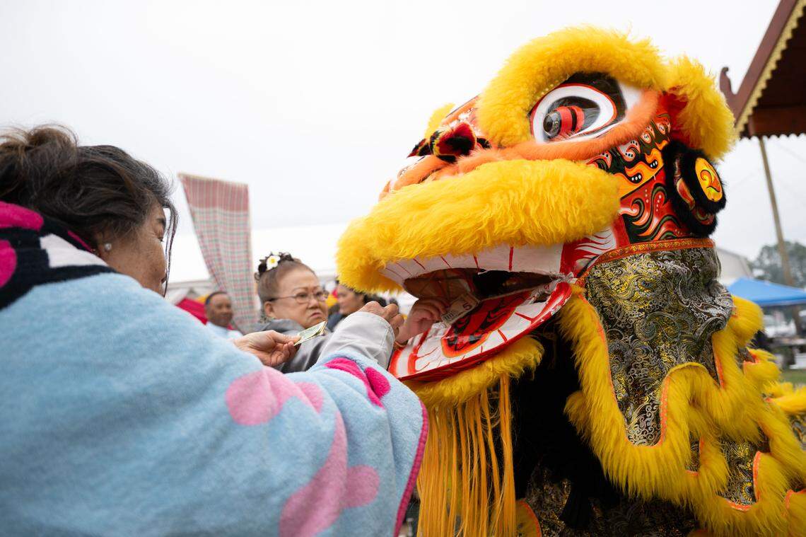 A man dressed as a dragon accepts money as he performs during Songkran at the Wat Buddhametta Mahabaramee in Gautier on Sunday, April 19, 2026.