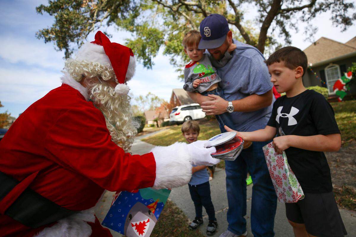 Santa (Phil Dellenger) gives Banks and Baylor Gomila presents outside of their Biloxi home Saturday, Dec. 19, 2020.
