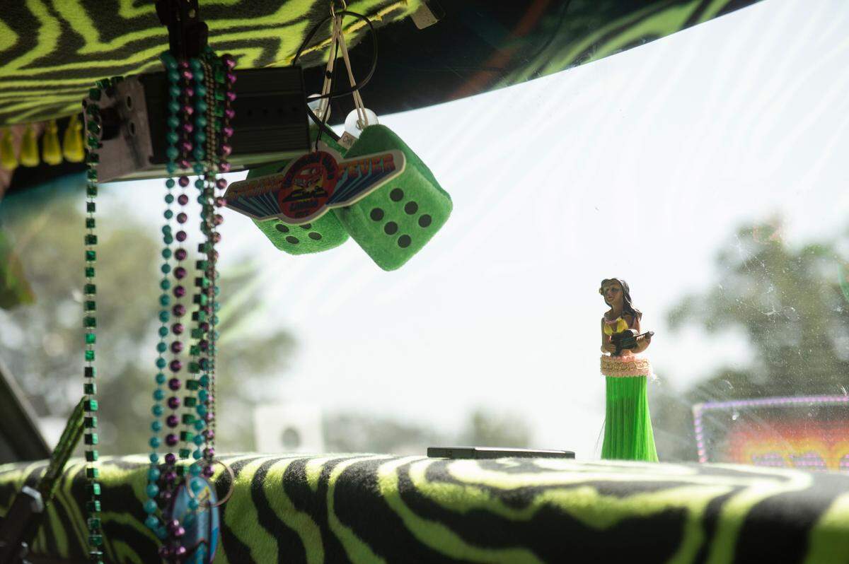 Accessories like fuzzy dice, a hula girl and Mardi Gras beads decorate a car at Cruise Central at Centennial Plaza during Cruisin’ the Coast.