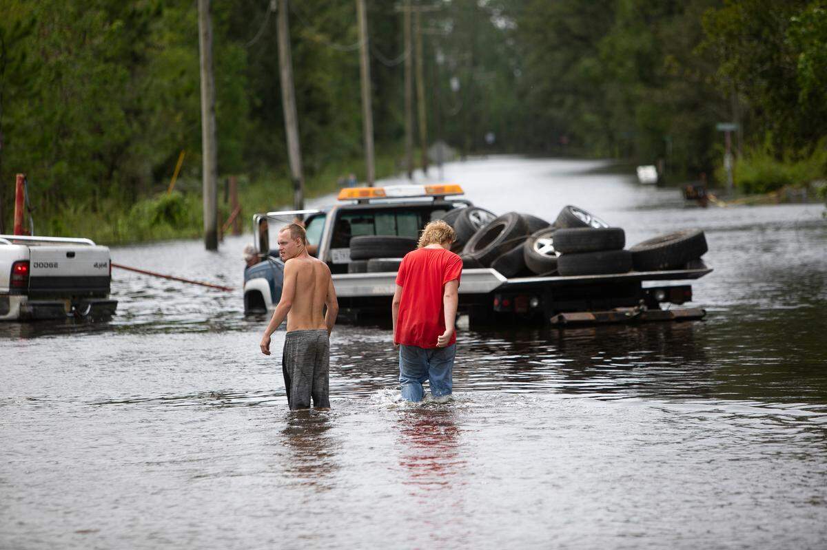 Men walk down a flooded street in the Shoreline Park community of Bay St. Louis after Hurricane Ida on Aug. 30, 2021.