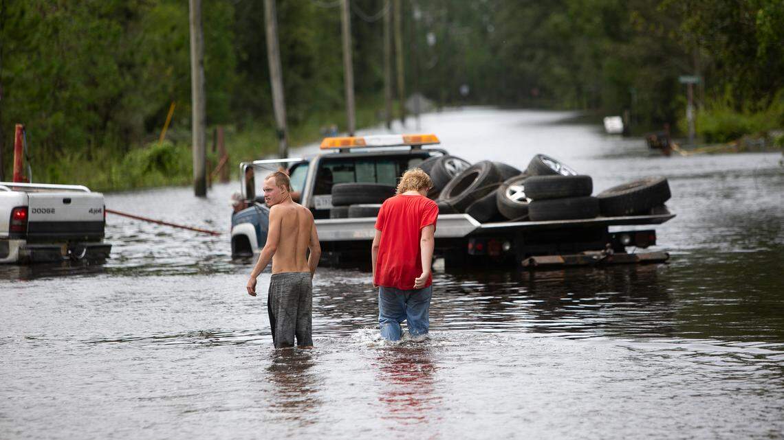 Men walk down a flooded street in the Shoreline Park community of Bay St. Louis after Hurricane Ida on Aug. 30, 2021.