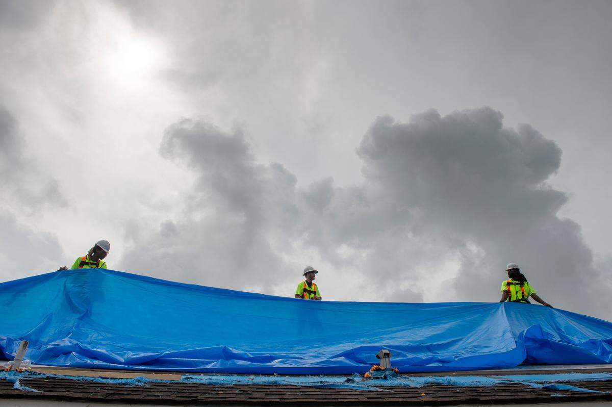 Roofing contractors install a temporary roof on a home in New Orleans on Wednesday, Sept. 8, 2021., after Hurricane Ida.