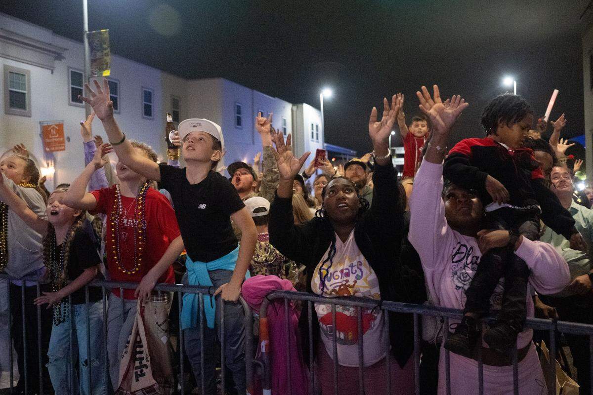 Crowds of people reach out for Mardi Gras beads tossed from parade floats during the Krewe of Neptune parade in Biloxi on Saturday, Feb. 14, 2026.