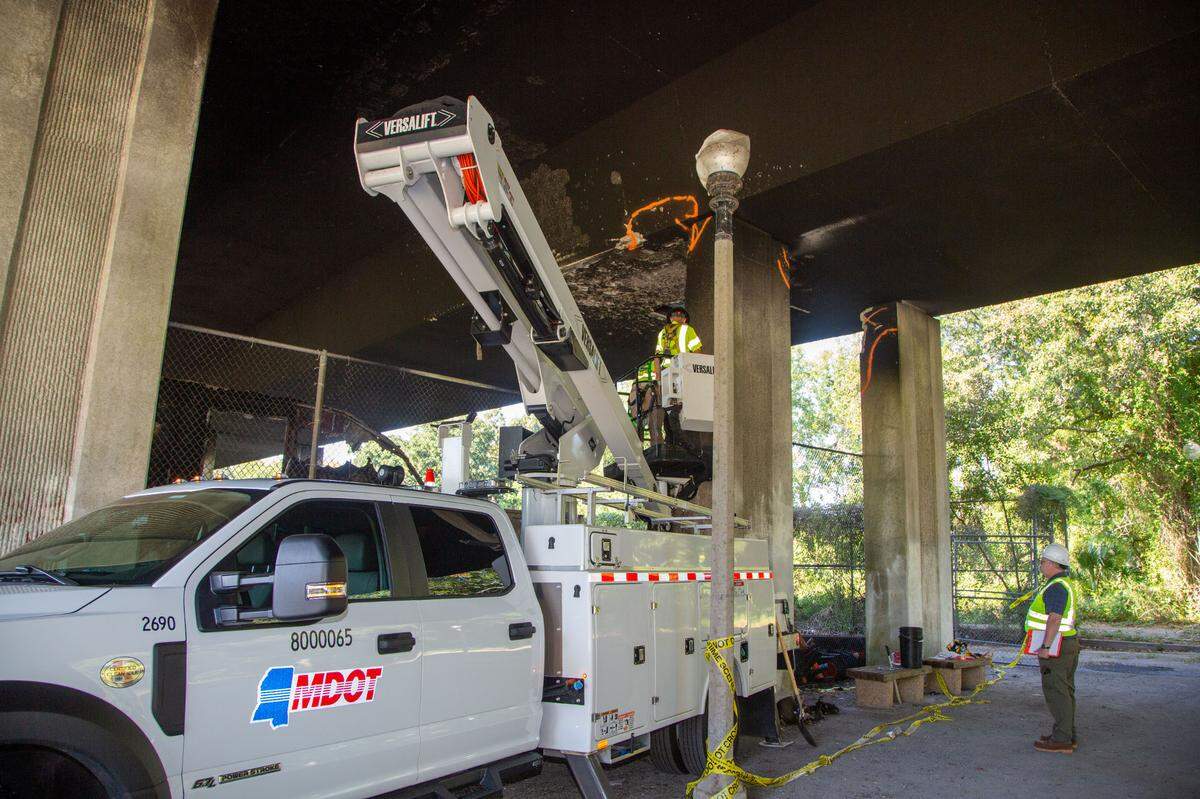 Inspectors from MDOT inspect the underside of the I-110 bridge following a fire that damaged the bridge. The bridge is currently closed to southbound traffic.