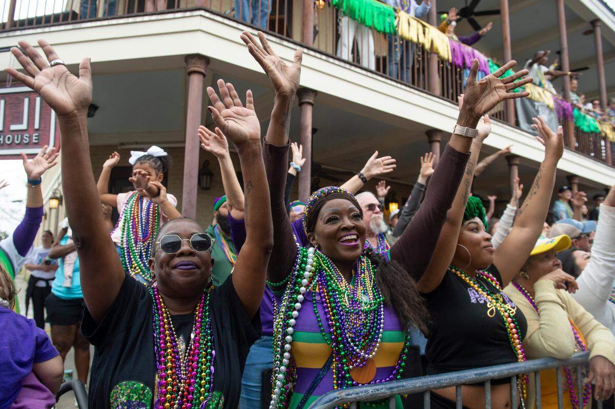 Parade watchers cheer for beads and other throws during the Gulf Coast Carnival Association Mardi Gras parade in Biloxi on Tuesday, March 4, 2025.