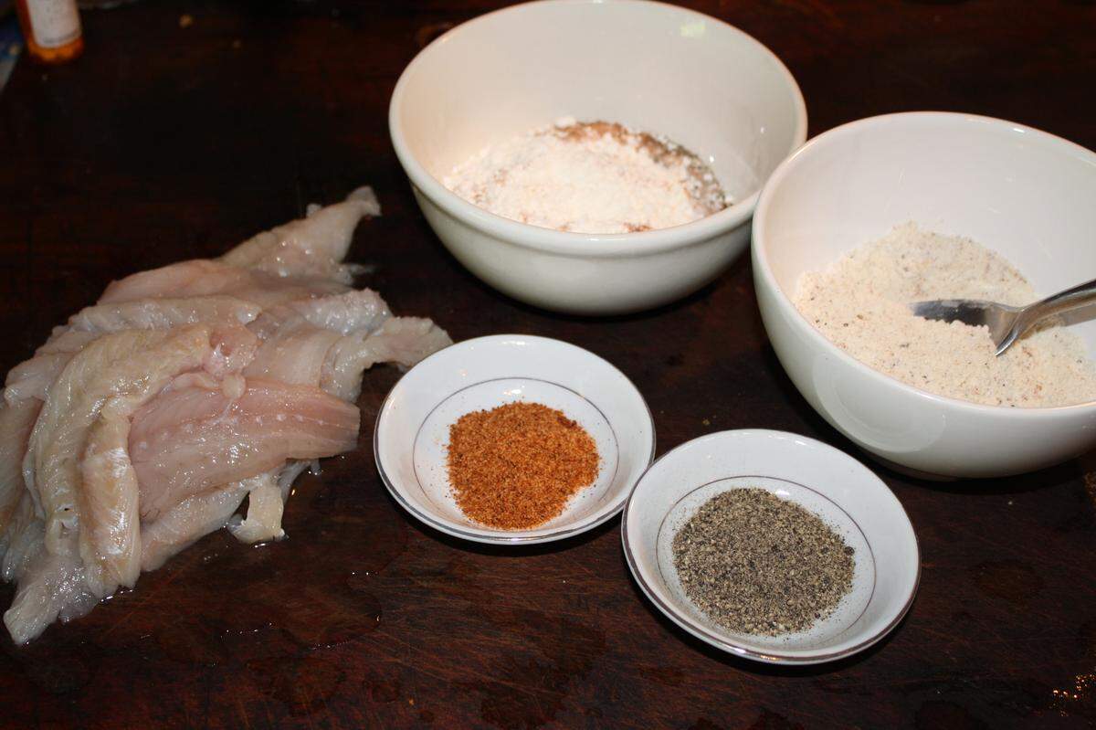 Mullet filets and spices and flour in preparation for frying.