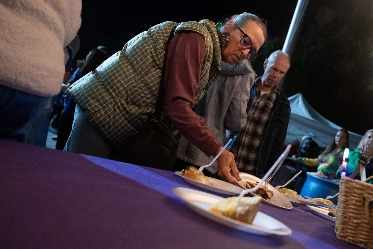 Event attendees pick up slices of King Cake during a 12th Night Celebration in Biloxi on Monday, Jan. 5, 2026.