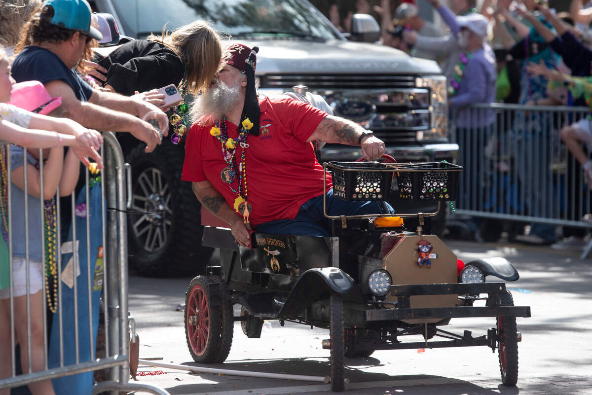 A member of the Joppa Shriners kisses a parade watcher during the Ocean Springs Elks Club Mardi Gras Parade in Ocean Springs on Saturday, Feb. 15, 2025.