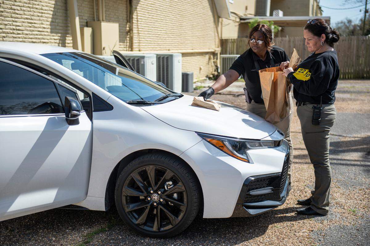 Crime scene investigators collect evidence from a white Toyota parked behind Leap of Faith School in Pascagoula on Monday, March 21, 2022. According to Lt. Cory Thompson, the vehicle could possibly be tied to a shooting that happened at the school, but an investigation to determine if there is a connection is ongoing.