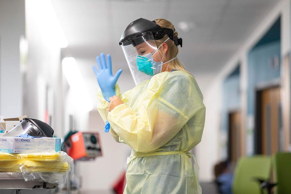 Infectious diseases nurse practitioner Spencer Brooks puts on personal protective equipment before checking on a COVID-19 patient in the intensive care unit at Children’s of Mississippi.