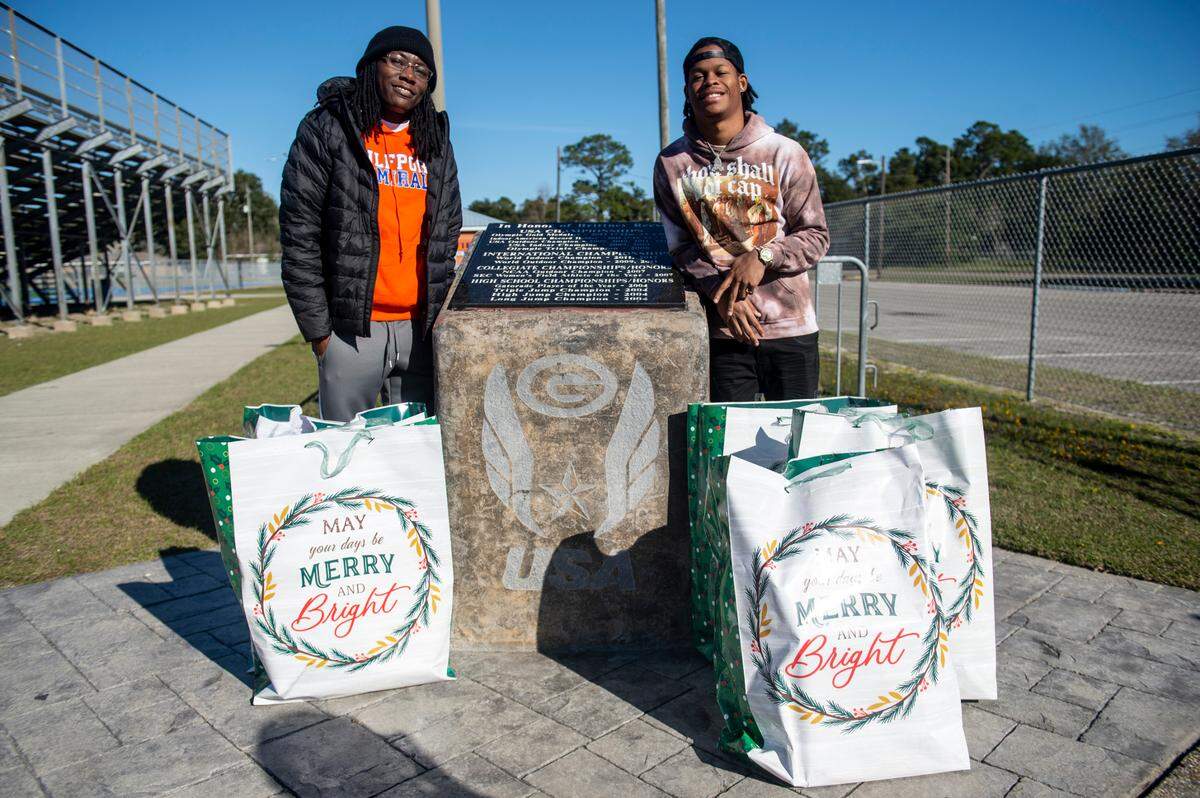 Olympian and Gulfport High School track coach Brittney Reese and Mississippi native rapper J. Lock pose with some of the Christmas presents they will deliver to needy families outside the Gulfport track in Gulfport on Friday, Dec. 23, 2022.