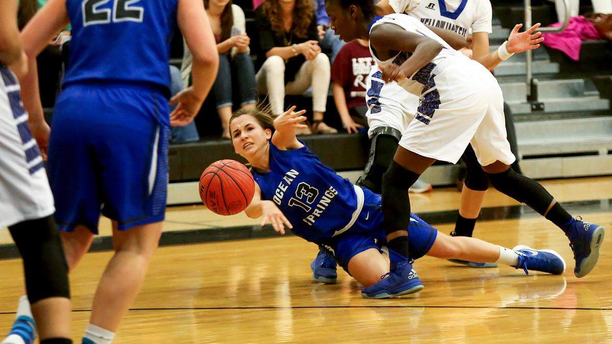 AMANDA McCOY/SUN HERALD 
 Ocean Springs' Sophie St. Amant passes the ball while falling to the floor after being pressured by the St. Martin defense, provided by Mercedes Brown, front, and Savannah Jones, on Friday, Feb. 19, 2016, at D'Iberville High.