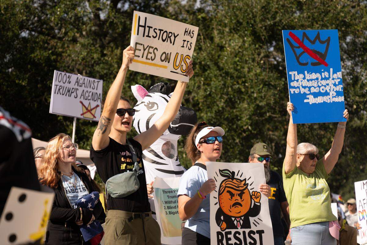 Protesters chant while holding up signs Saturday.