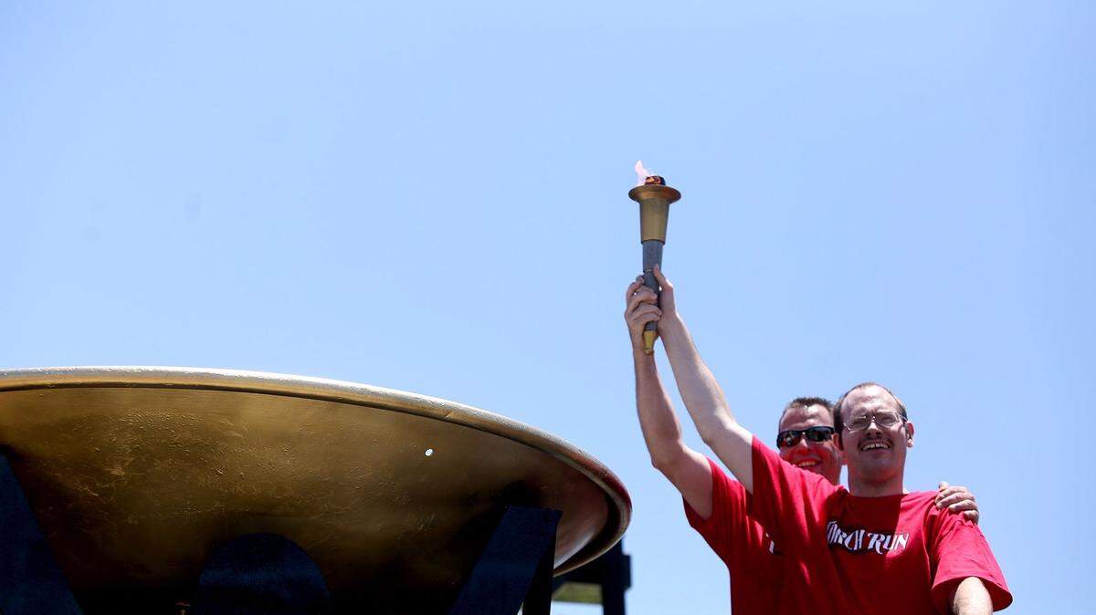 AMANDA McCOY/SUN HERALD 
 Brig. Gen. Patrick C. Higby, former commander of the 81st Training Wing, left, and athlete Perry May, celebrate the lighting of the cauldron for the 2015 Special Olympics State Summer Games on May 8, 2015. This year's event will kick off at 7:30 p.m. Friday with the lighting of the cauldron at Keesler Air Force Base.