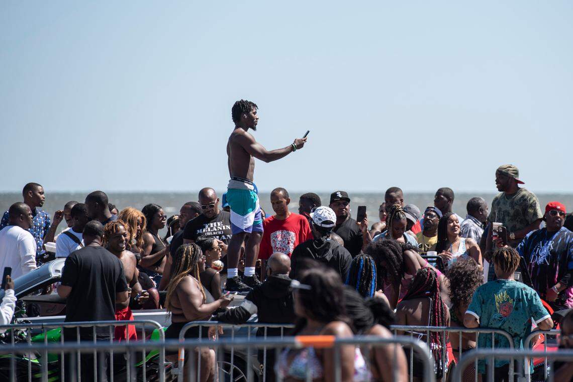 Spring breakers take photos of cars parked along Highway 90 during Black Spring Break in Biloxi on Saturday, April 9, 2022.