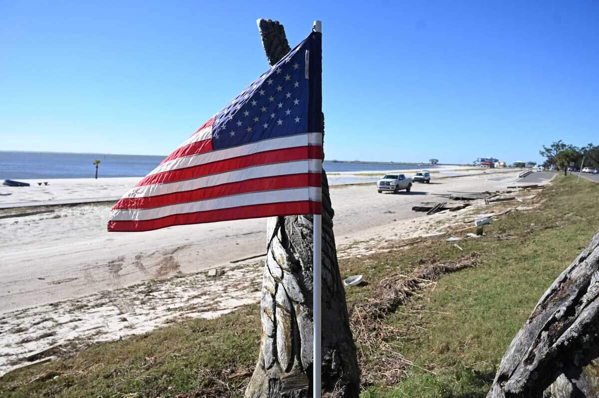 An American Flag flies in the median of Highway 90 in Long Beach as the eastbound section of the road is covered in sand from Hurricane Zeta Oct. 28, 2020.