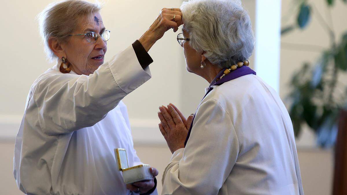 AMANDA McCOY/SUN HERALD 
 Dorothy Fox, left, applies ashes onto Pastor Barb Gibson's forehead during an Ash Wednesday service at Bethel Lutheran Church on Wednesday, Feb. 10, 2016. This was the first year that the church held a noon service.