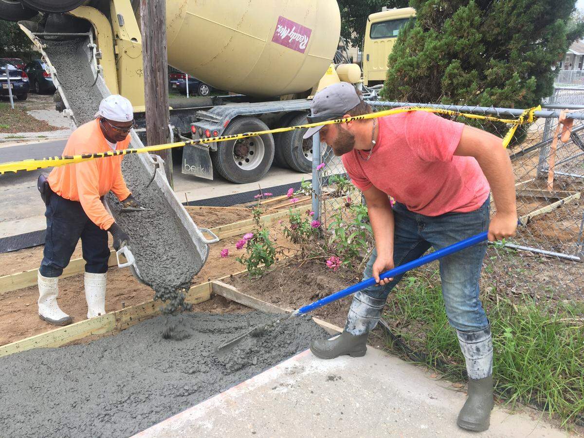 Brandon Farley, right, and his DNA Underground colleagues poor concrete outside John Higgins’s house in October 2021. The crew has been fixing sidewalks and driveways that were built improperly during East Biloxi’s years-long infrastructure repair project.