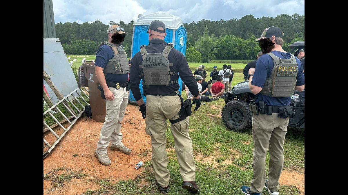 Law enforcement agents, whose faces have been blurred by U.S. Immigration and Customs Enforcement, are on the scene of an alleged cockfighting operation on Saturday in Harrison County.