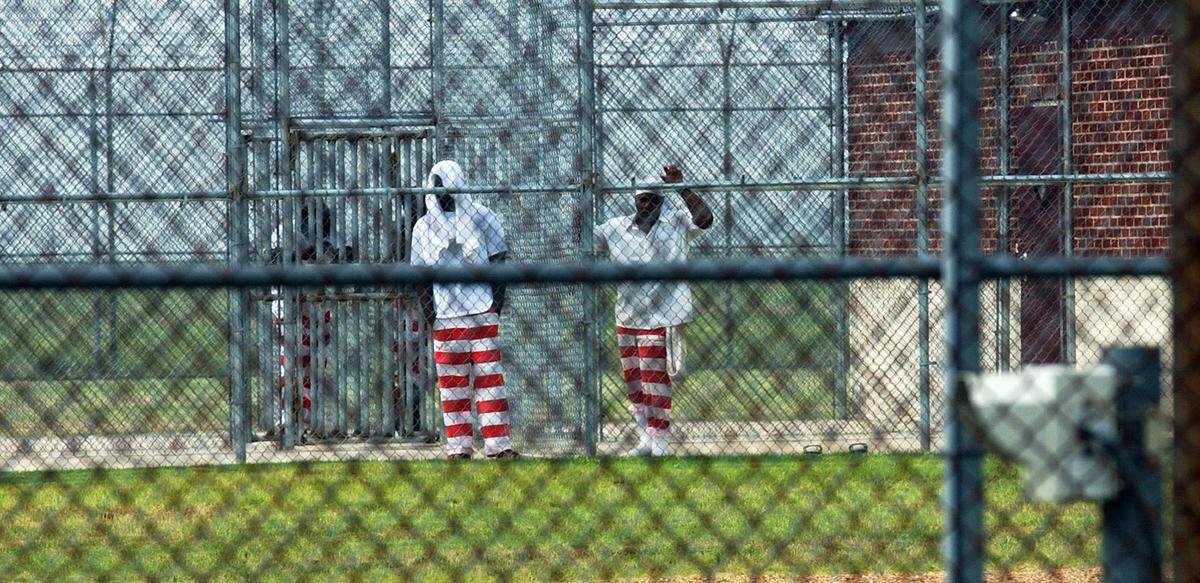 Maximum security inmates at Mississippi State Penitentiary’s Unit 17 peer through the security fences in 2002 in Parchman.