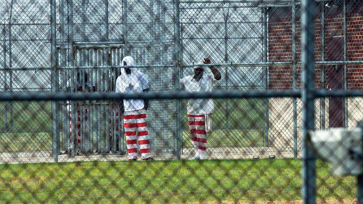 Maximum security inmates at Mississippi State Penitentiary’s Unit 17 peer through the security fences in 2002.