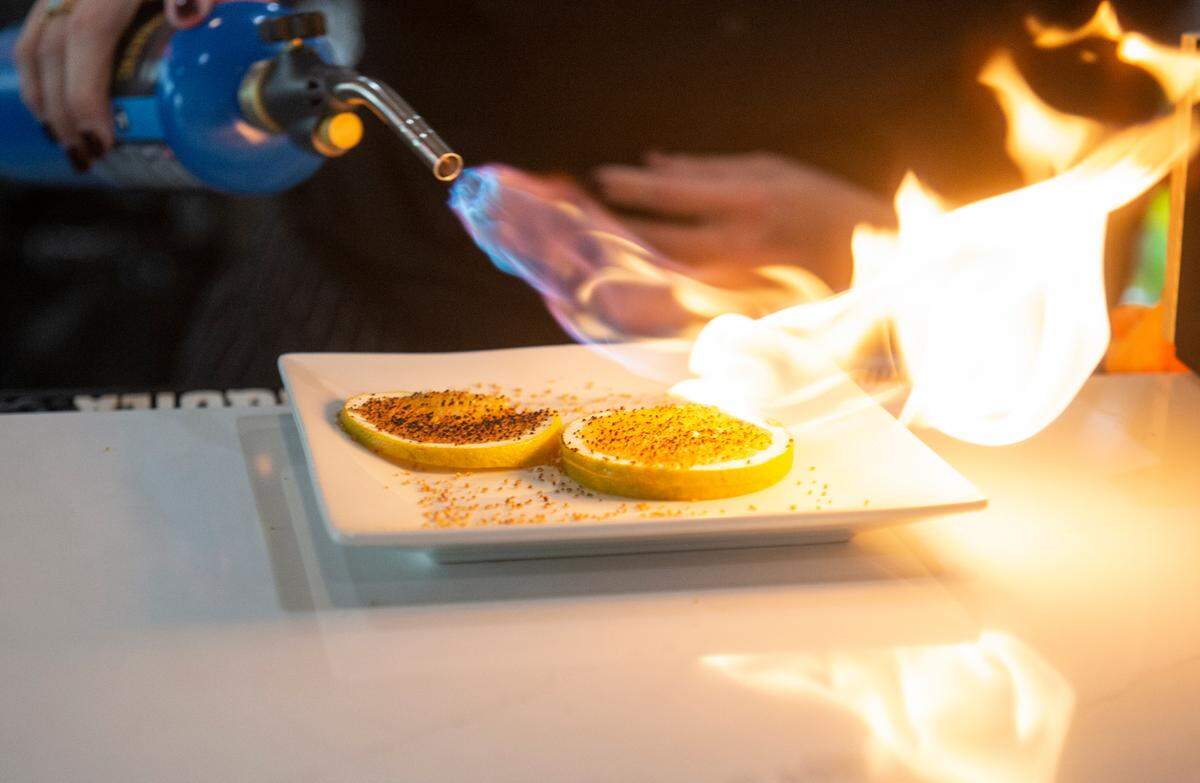 A bartender torches citrus slices for a seasonal pumpkin spice old fashioned cocktail at Mangiamo, a new Italian restaurant in Gulfport, on Friday, Nov. 4, 2022. It is one of several new restaurants that opened on Cowan Road this year.
