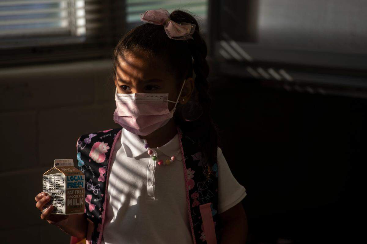 A student wears a mask as she waits for her free lunch on the first day of school.