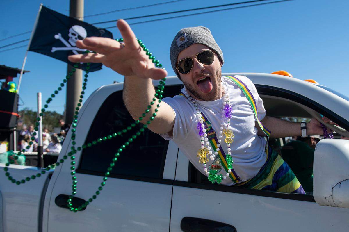 A man helping tow a float tosses beads during the Krewe of Nereids Mardi Gras parade on Highway 90 in Bay St. Louis on Sunday, Feb. 12, 2023.