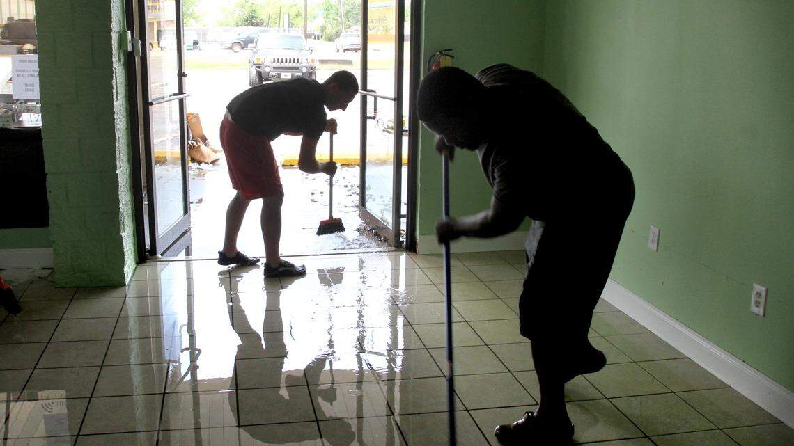 TIM ISBELL/SUN HERALD 
 Dustin Knowles and Antonio Barnes sweep water out of Melissa's Bakery on Dedeaux Road in Gulfport, Thursday, Apr. 28, 2016. The bakery was flooded by torrential rain which hit the area Thursday morning.
