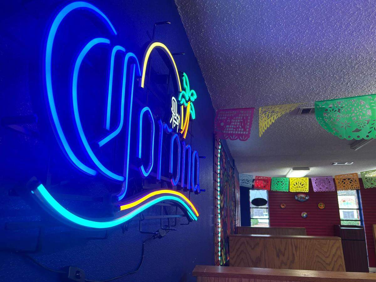 The interior of Los Sarapes Tacos y Mas in Gulfport, Mississippi features neon lights and tapestry.