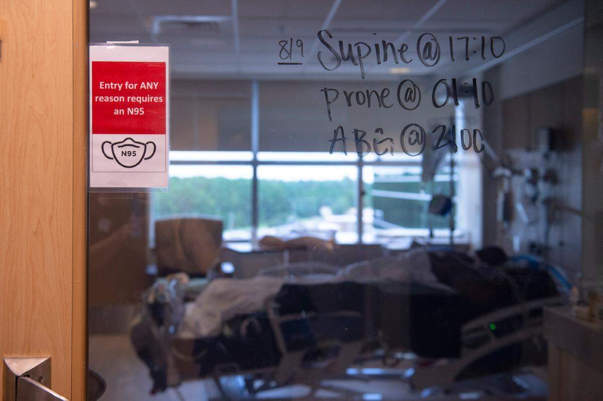 Care information and a sign requiring masks on a COVID-19 patient’s room in the ICU at Memorial Hospital in Gulfport on Wednesday, Aug. 11, 2021.
