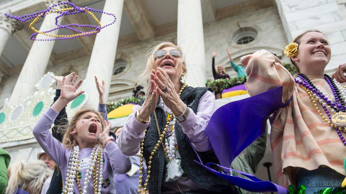 Parade watchers cheer for beads and other throws during the Gulf Coast Carnival Association Mardi Gras parade in Biloxi on Tuesday, March 4, 2025.