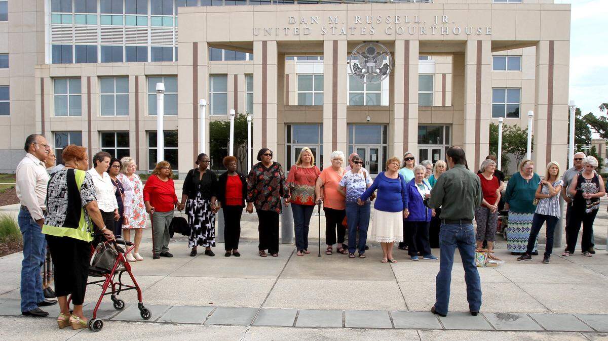 TIM ISBELL/SUN HERALD 
 Members of Singing River Health System's pension plan join hands and pray before entering the federal courthouse in Gulfport on Monday, May 16, 2016, for a hearing on a proposed class-action settlement involving their retirement benefits. A federal judge approved the settlement Thursday.