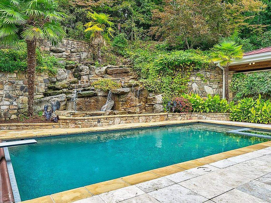 The home features an outdoor kitchen, cabana, heated in-ground pool and a two-story waterfall.