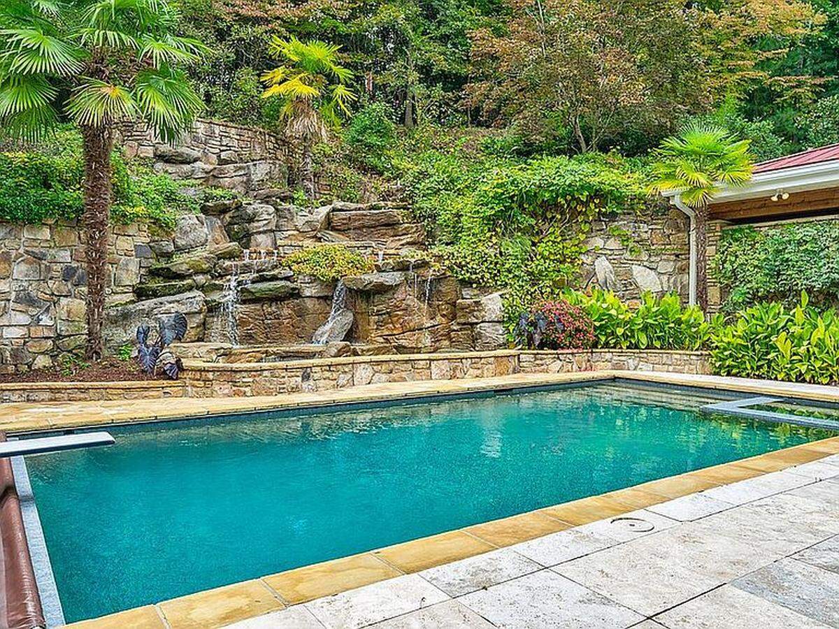 The home features an outdoor kitchen, cabana, heated in-ground pool and a two-story waterfall.