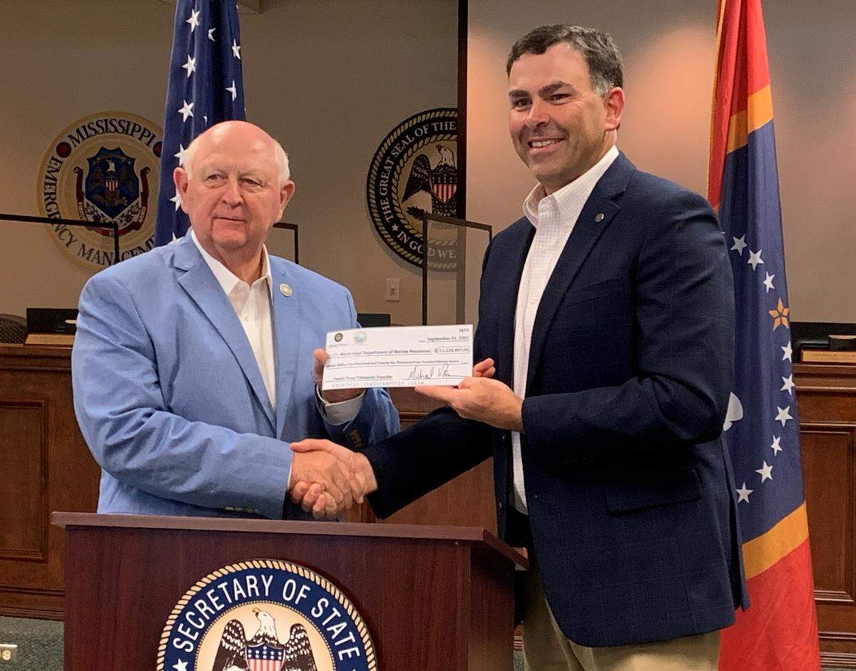 Secretary of State Michael Watson, right, hands a check for $11.2 million to Joe Spraggins, executive director of the Department of Marine Resources in 2021. to pay for piers, parks and other projects coastwide. There will be no check presentation this year.