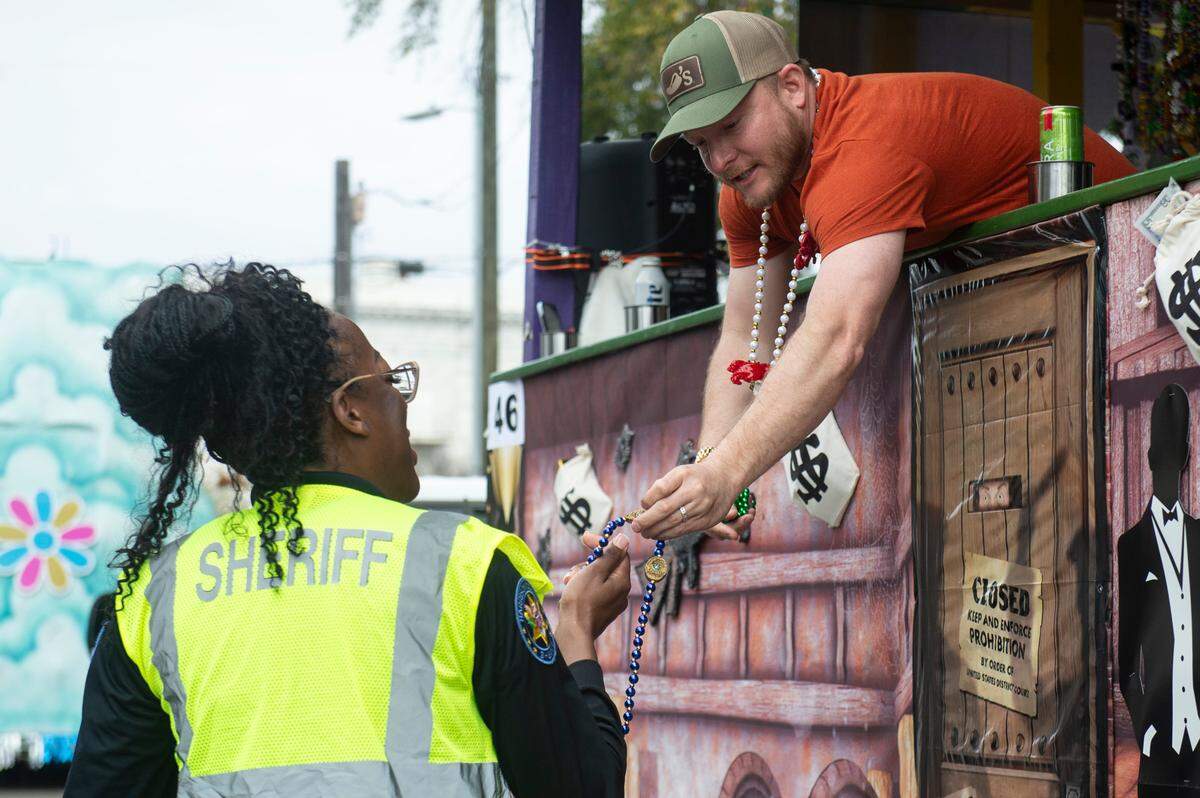 A float rider gives a member of the Harrison County Sheriff’s Department a law enforcement themed strand of beads during the Gulf Coast Carnival Association Mardi Gras parade in Biloxi on Tuesday, March 4, 2025.