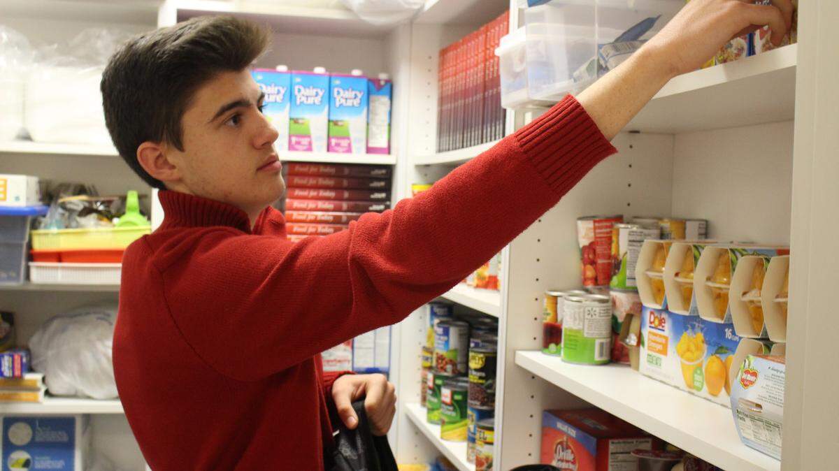 JEFF CLARK/SUN HERALD 
 Hayes Leyser, a Pass Christian High School freshman, fills backpacks with food items for needy students to take home each week.