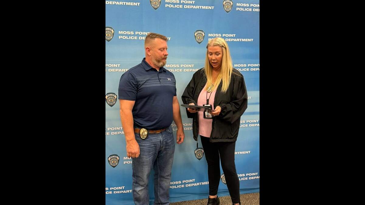 Former Moss Point Police Detective Sgt. Kimberlee Snowden presents former Moss Point Police Chief Brandon Ashley with a plaque honoring his service on his last day on the job on Oct. 3, 2025. The police officers chipped in to buy him the plaque.