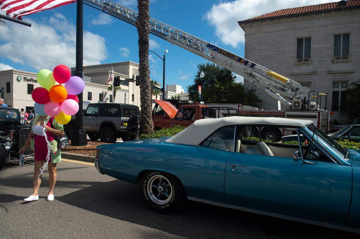 A woman holds balloons during View the Cruise, one of the first events of Cruisin’ The Coast, in Gulfport on Sunday, Oct. 6, 2024.