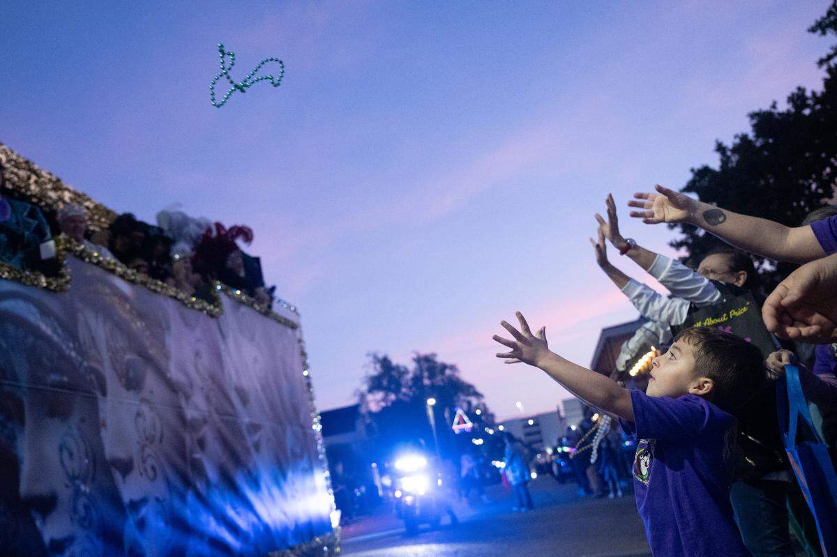 Joseph Simmons reaches out to catch a string of Mardi Gras beads during a 12th Night Celebration in Biloxi on Monday, Jan. 5, 2026.