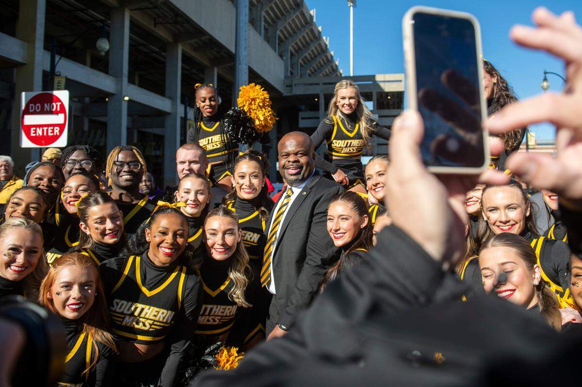 Southern Miss cheerleaders pose with Southern Miss’ new head football coach Charles Huff during a public welcome celebration for Huff at The Rock in Hattiesburg on Thursday, Dec. 12, 2024.