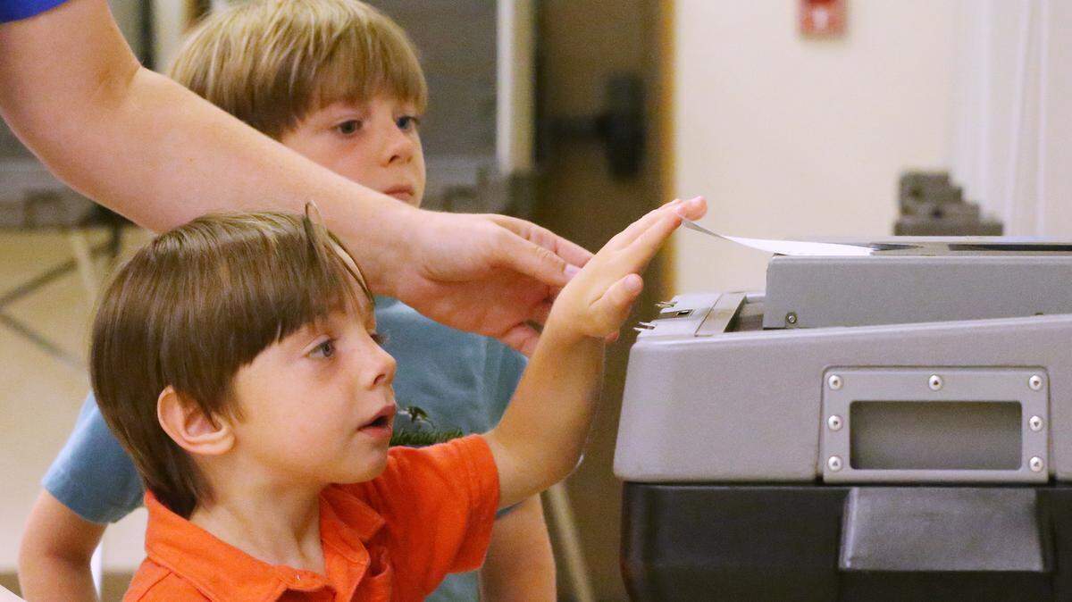 Luke Arnold, 3, and his brother, Case, 6, watch on Tuesday, June 5, 2018 as their mother, Jessica's, ballot goes into the counting machine at United Methodist Church in Long Beach. Party primaries for U.S. Senate and House of Representatives were held in Mississippi on Tuesday.