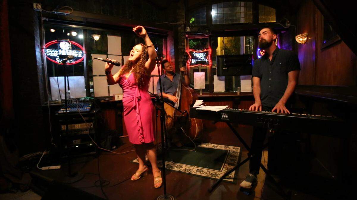 Courtney Weaver, a domestic violence survivor, performs her original music during an open mic at the Columbia City Theater. "It felt very personal that he was trying to make my voice go away," she said of a former abusive boyfriend who shot her in the face and arm. (Sy Bean/Seattle Times/TNS)