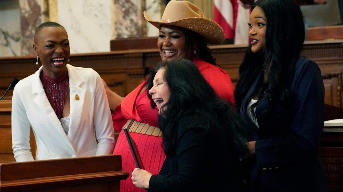 State Sen. Angela Hill, R-Picayune, foreground, laughs with members of the country music harmony group, Chapel Hart, as she presents them with a resolution on the Senate floor at the Mississippi Capitol in Jackson, Miss., Wednesday, Jan. 4, 2023. The group’s members, Trea Swindle, left, her cousins Danica Hart, center, and her sister Devynn Hart, are from Poplarville, and made national entertainment headlines when they made the finals of a national talent show. (AP Photo/Rogelio V. Solis)